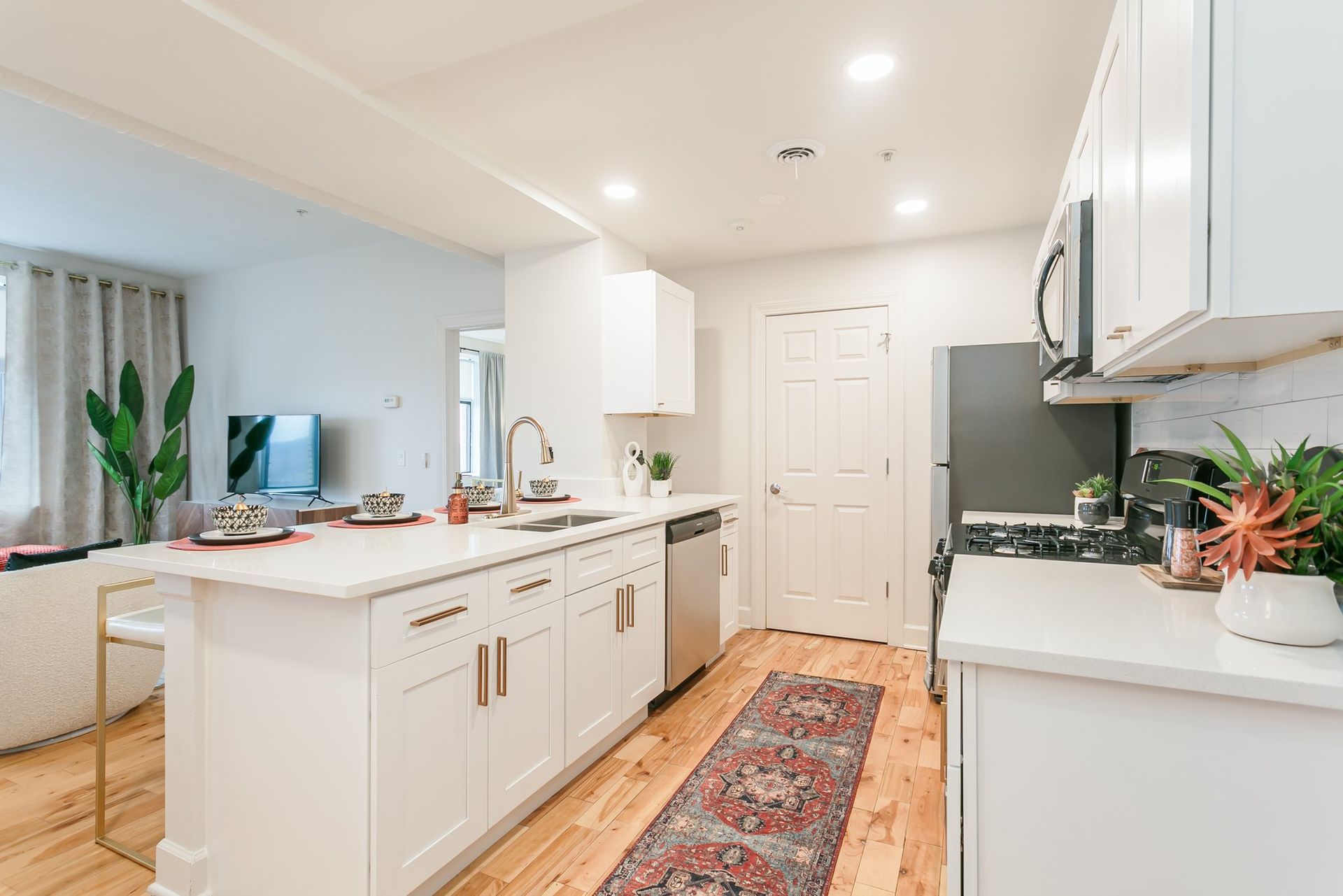 Modern kitchen with stainless steel appliances, marble countertops, and hardwood floors