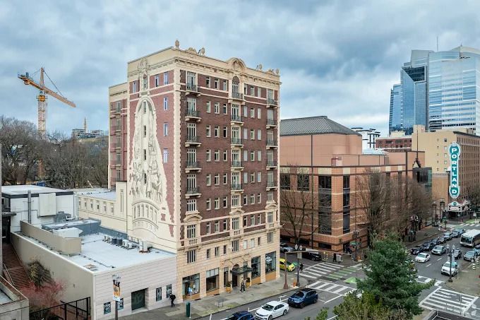 Brick building with ornate facade, near other buildings and street traffic.