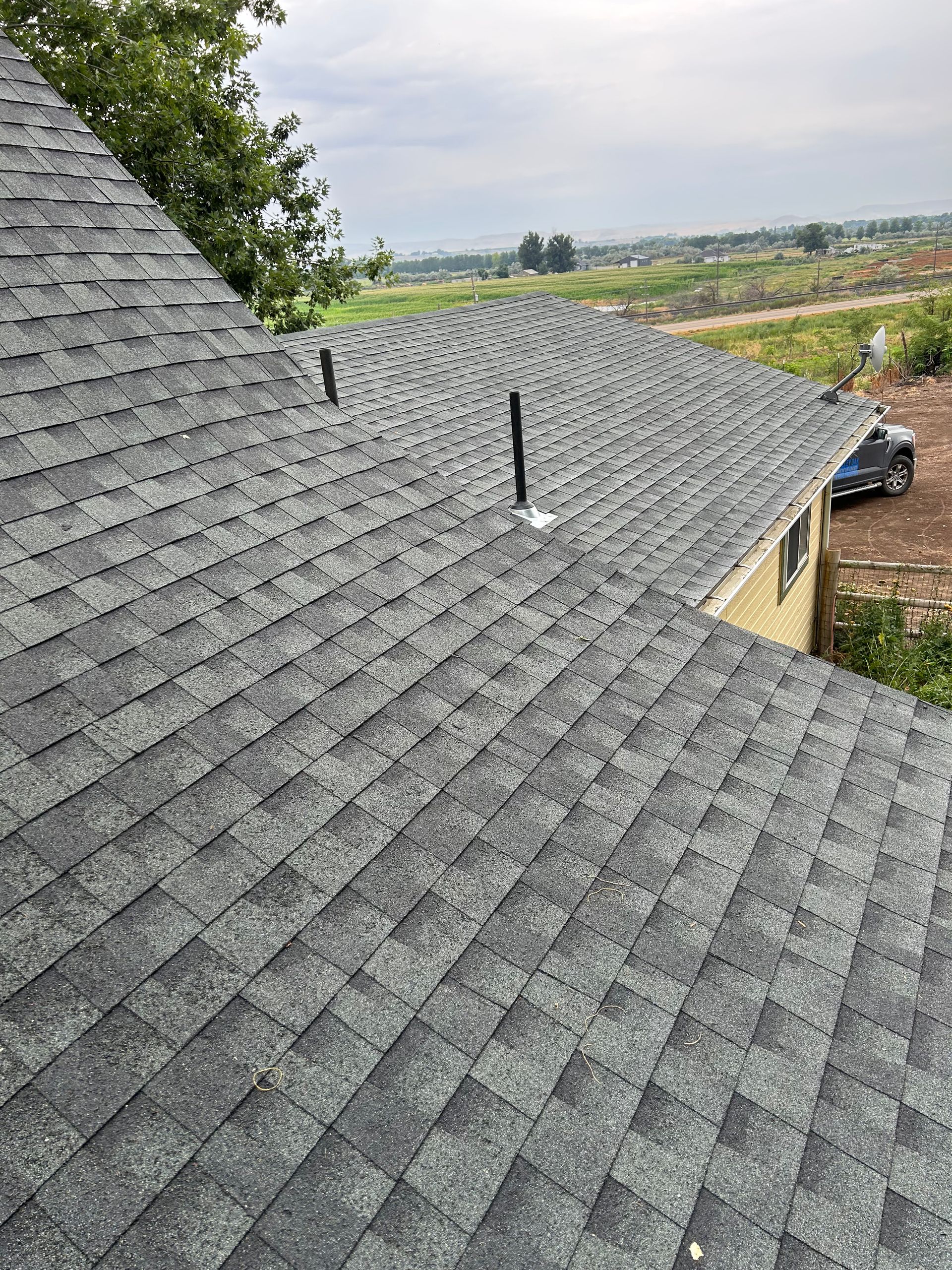 Slate roof with two black vents overlooking a rural landscape