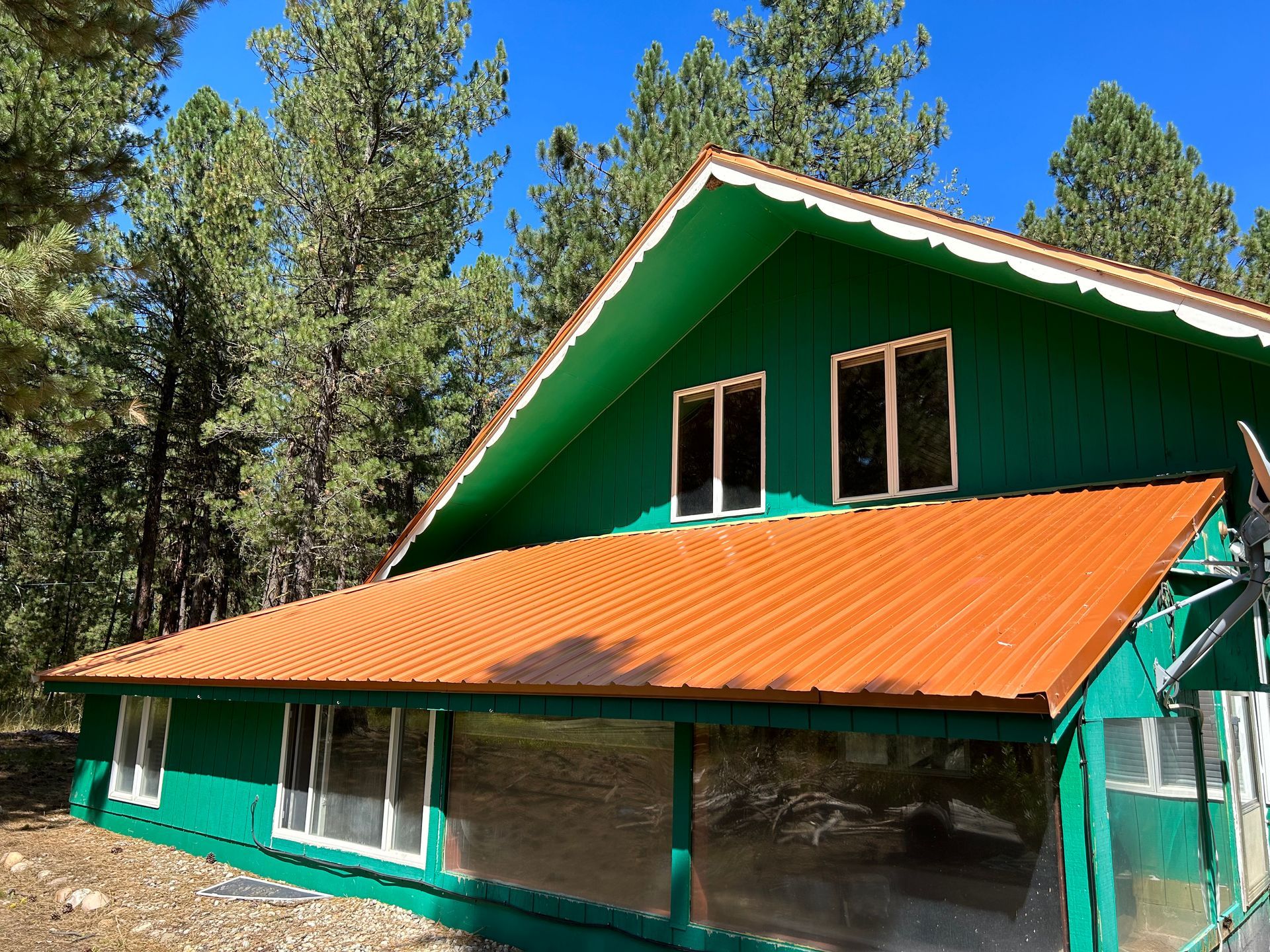 Green cabin with orange roof in a forested mountain setting