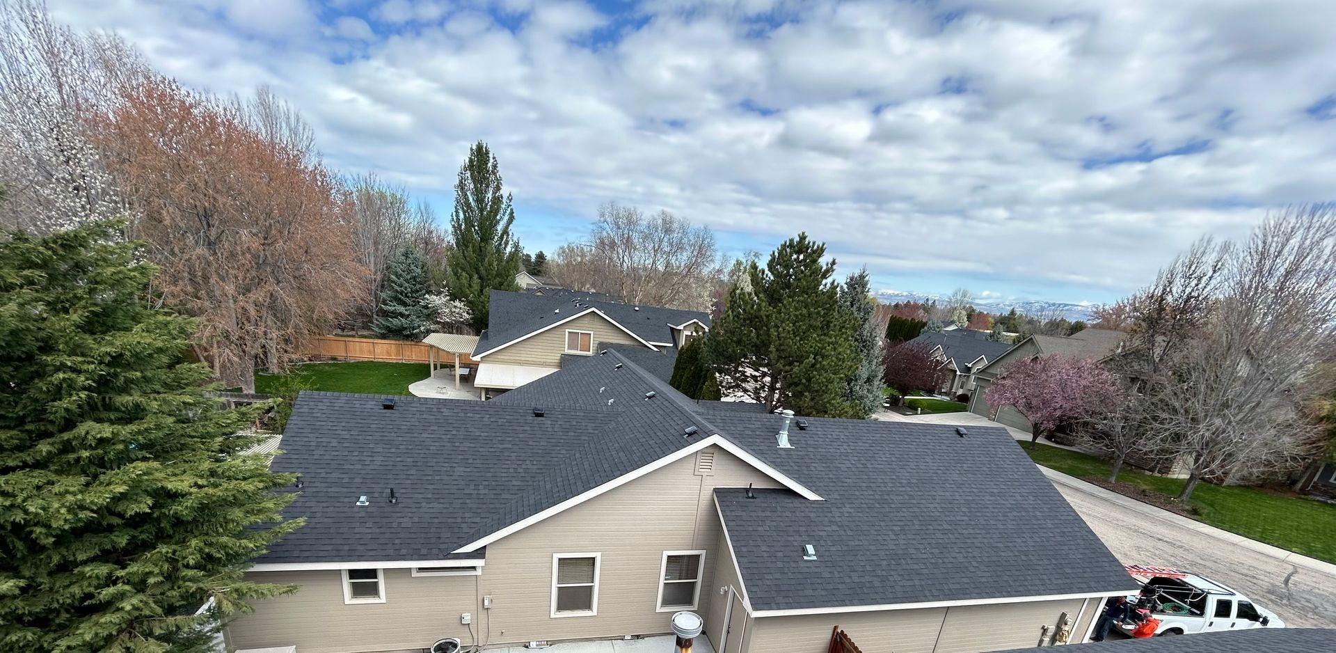 Suburban rooftops under a partly cloudy sky with trees in spring bloom