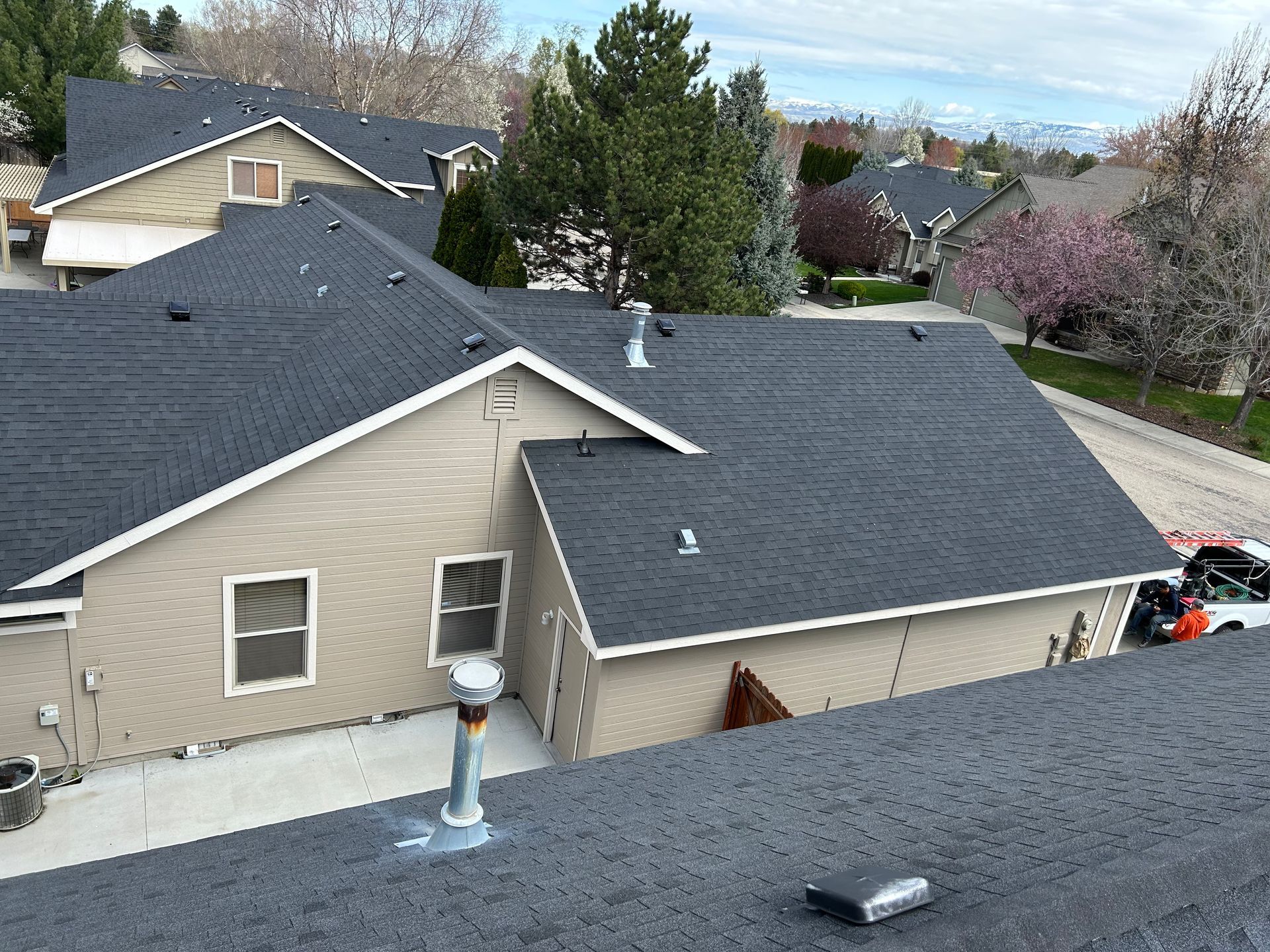 Aerial view of beige houses with dark roofs in a suburban neighborhood.