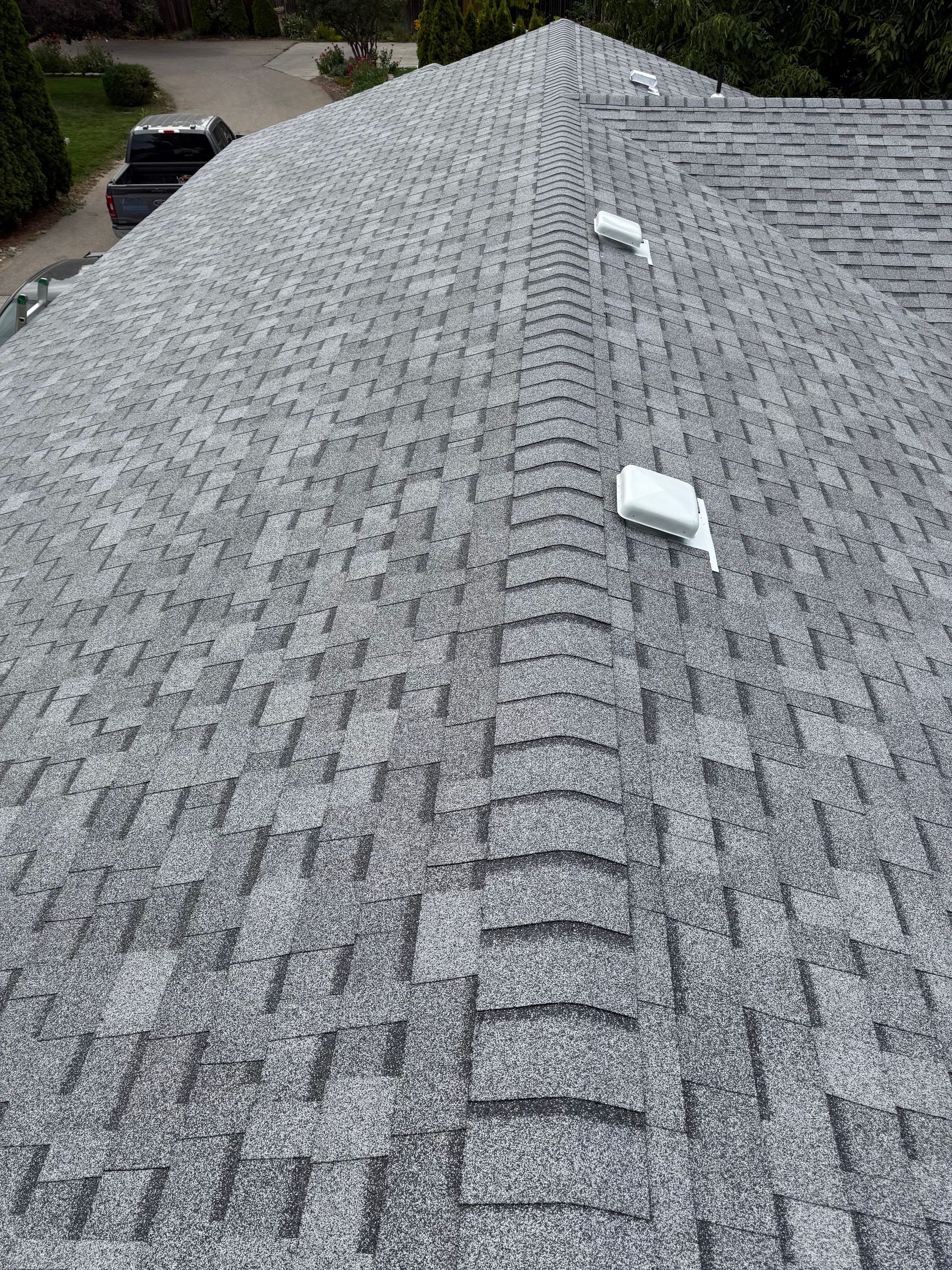 Gray shingled roof with a central ridge vent and two white roof vents near the top