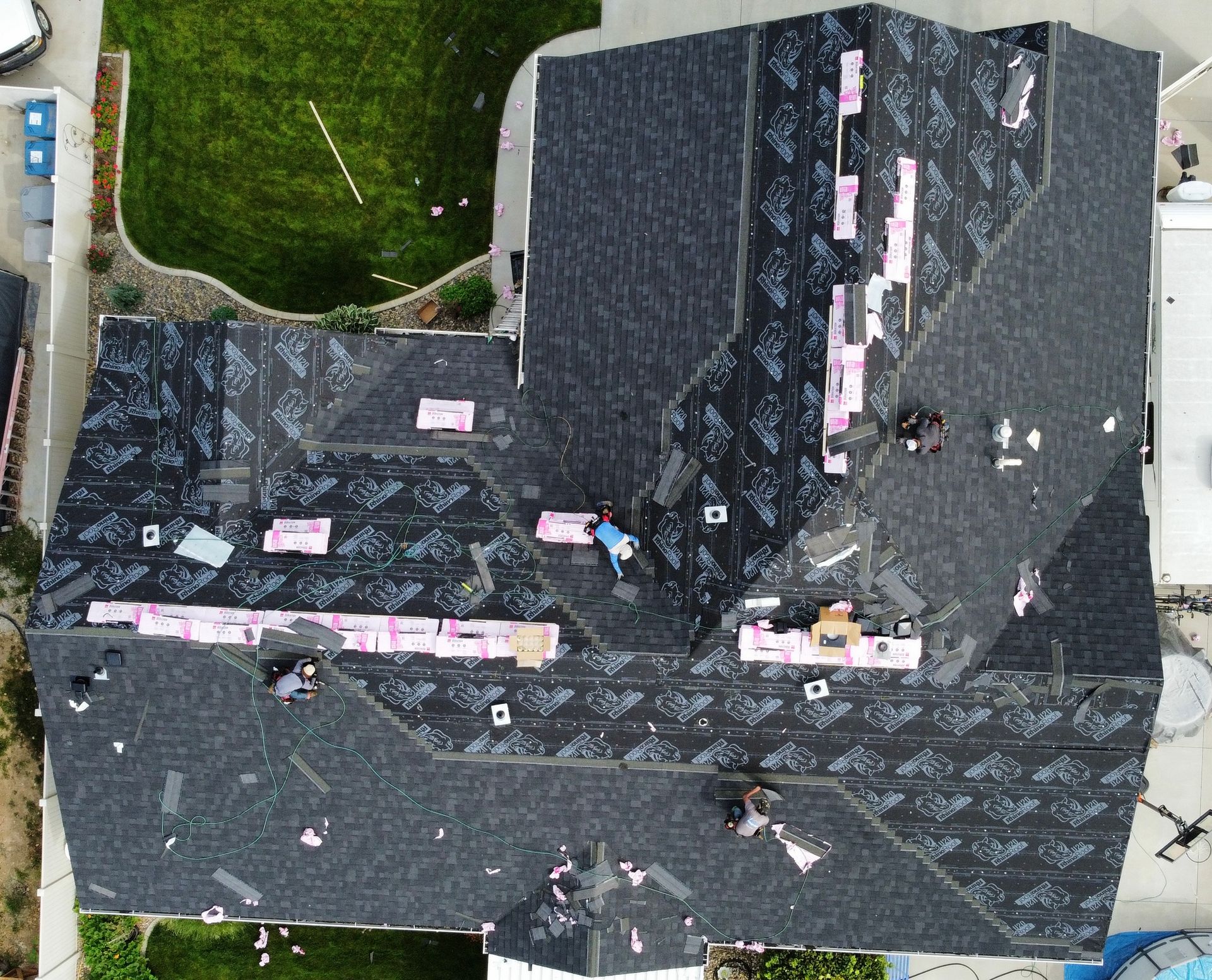 Aerial view of a dark-shingled house roof with scattered pink labels or markers.