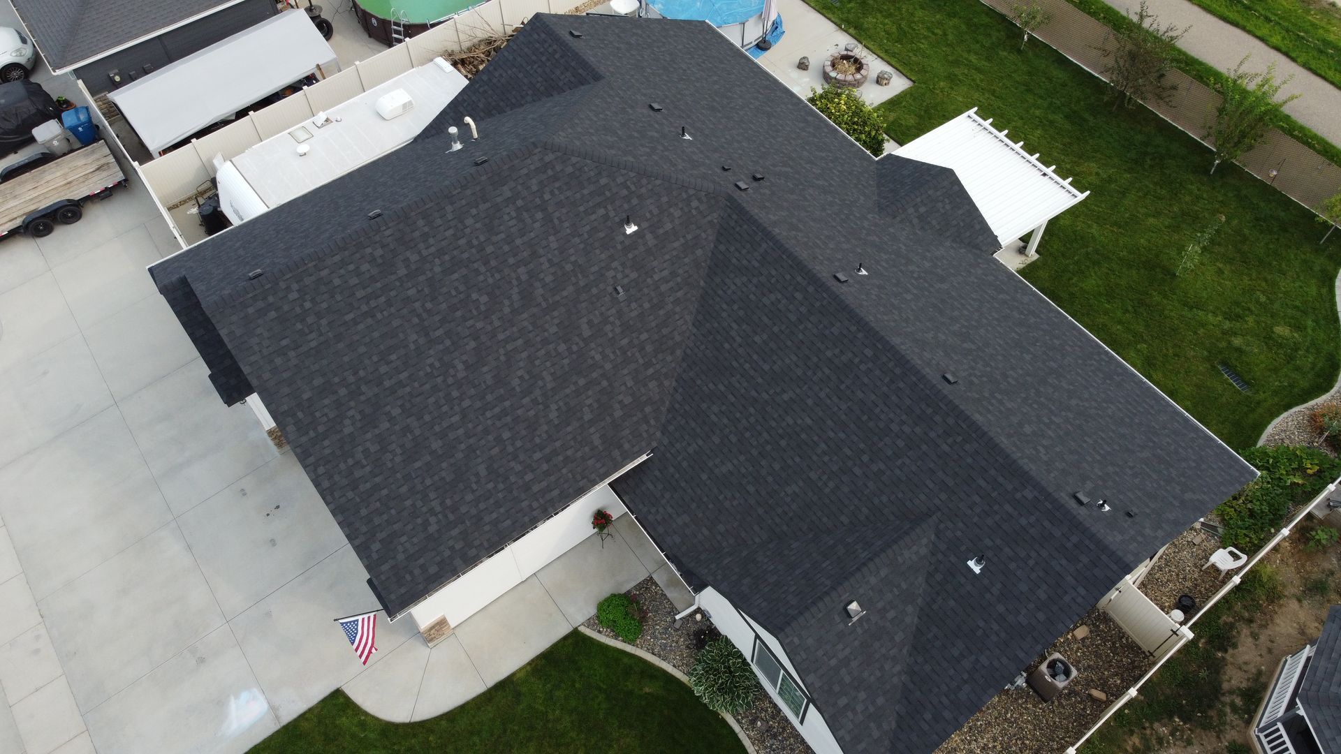 Aerial view of a dark gray roof on a suburban house with driveway and lawn.
