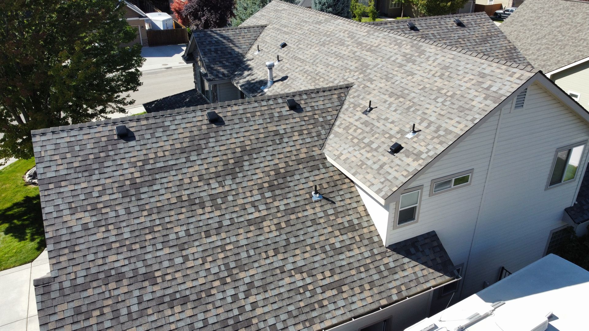Aerial view of a house roof with gray shingles and a white dormer.
