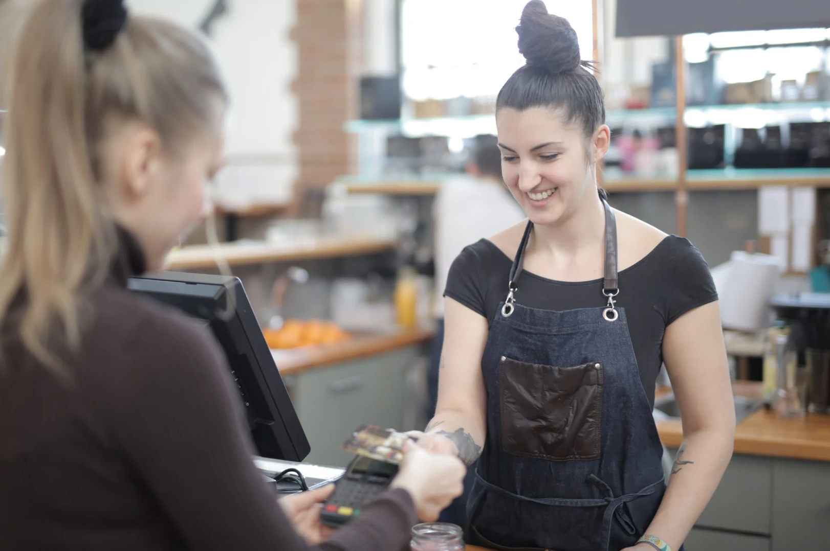 A woman is giving a credit card to another woman in a restaurant.