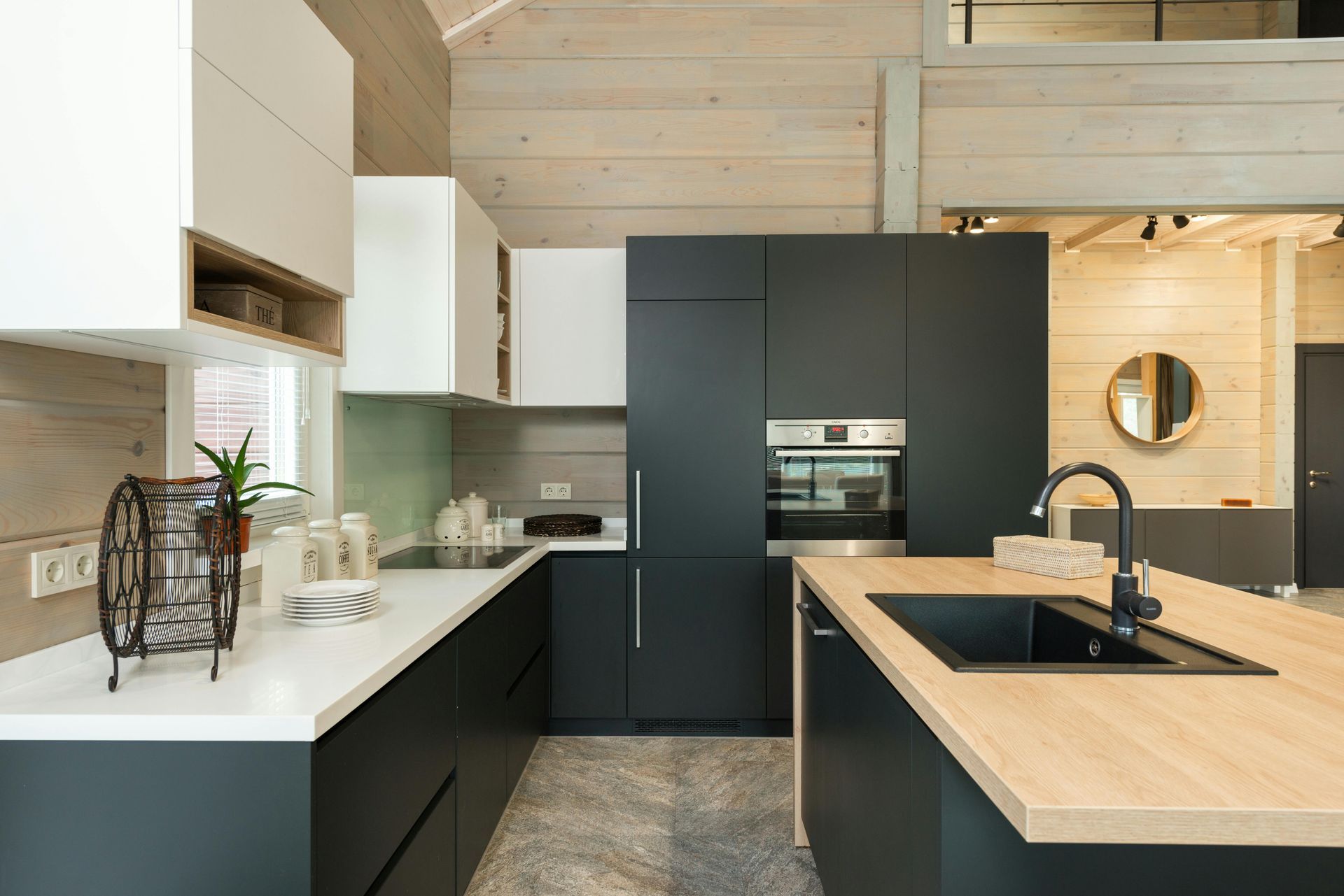 Modern kitchen with dark cabinets, light wood island, white countertops, and stainless steel appliances.