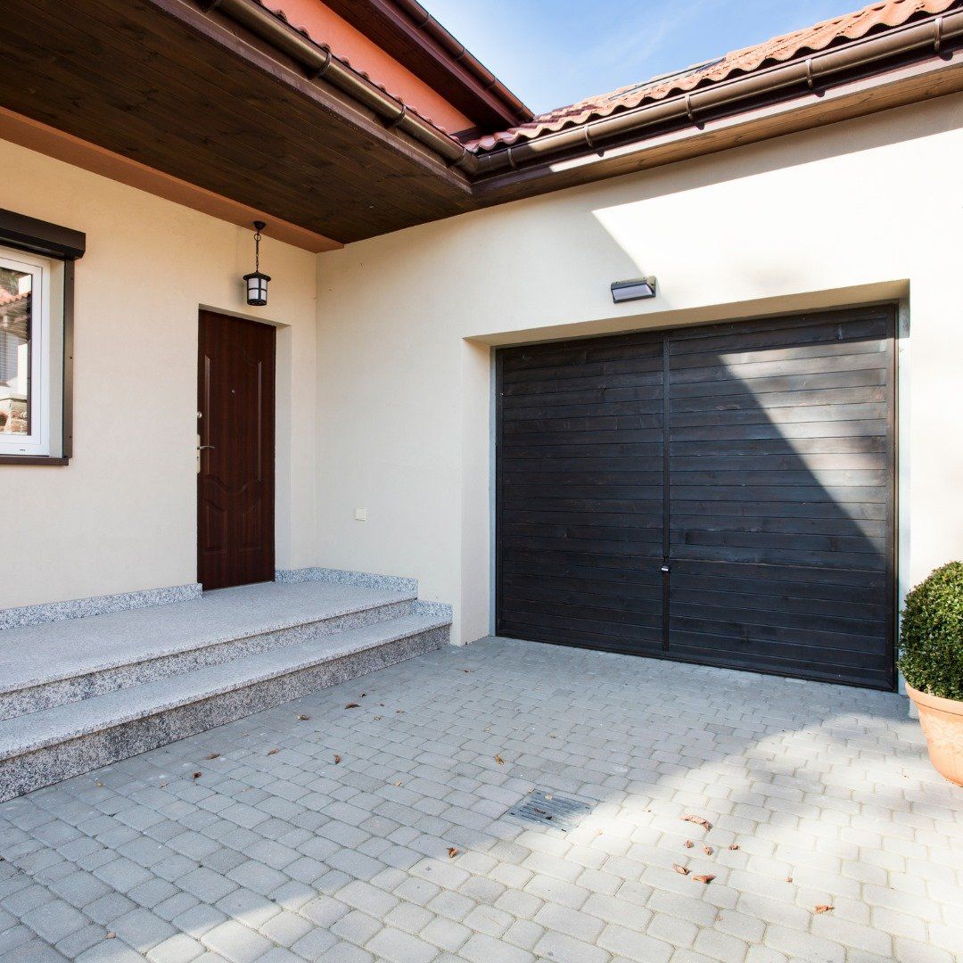A house with a black garage door and a brick driveway