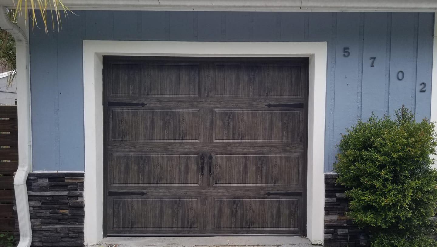A garage door is sitting in front of a blue house.