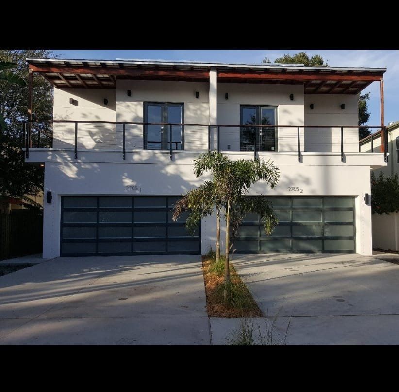 A white house with a black garage door and a balcony
