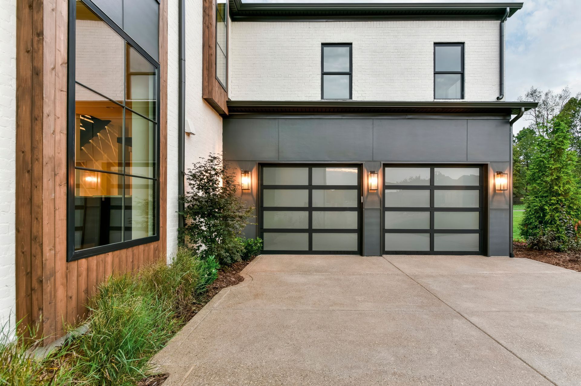 A row of new garage doors with windows on a house.