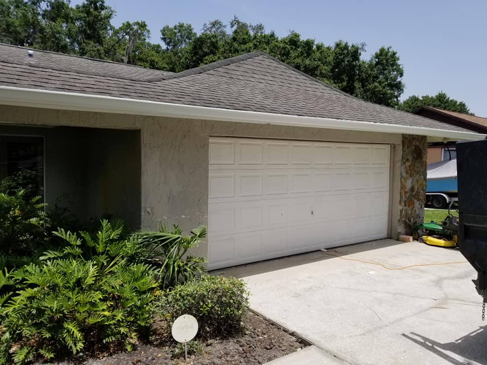 A white garage door is sitting in front of a house.