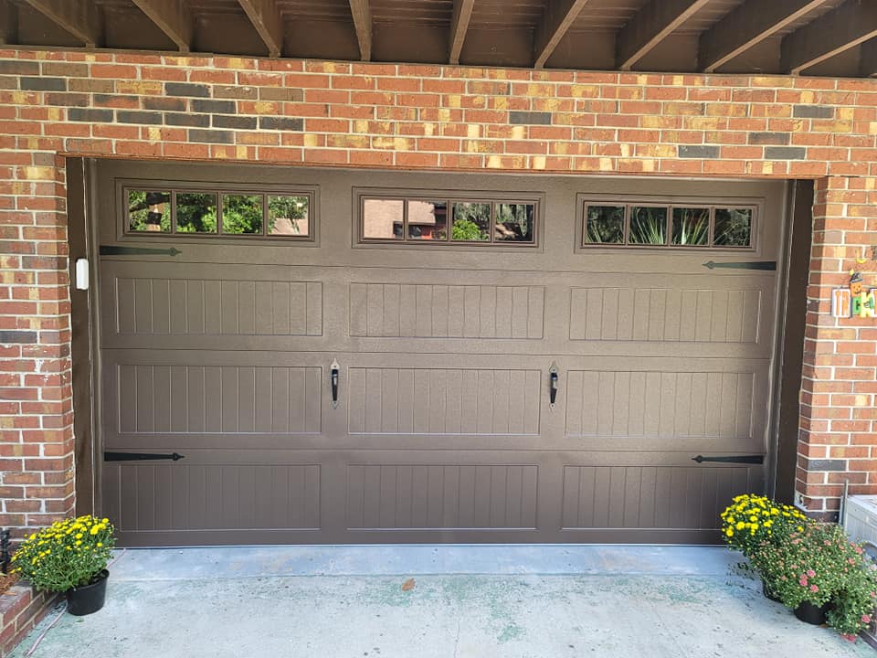 A brown garage door with a brick wall behind it