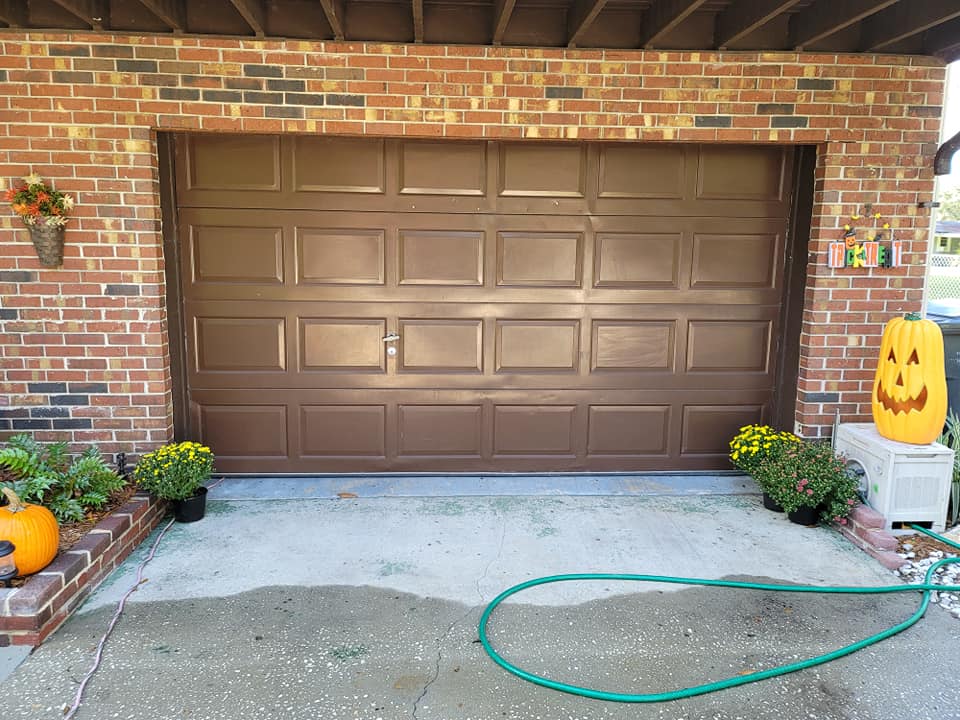 A brown garage door with a hose in front of it.