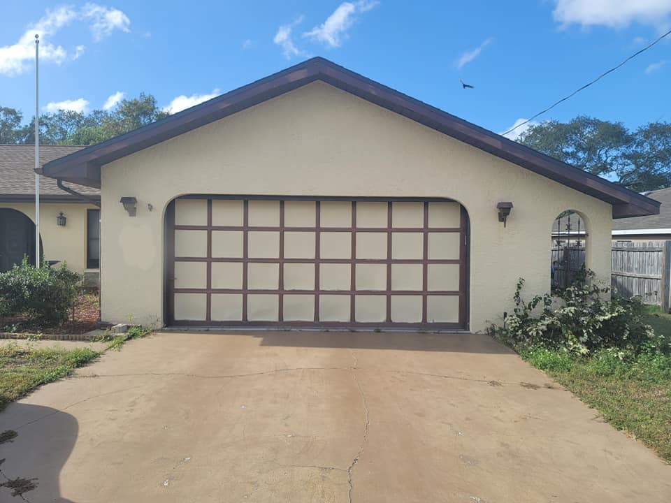 A white house with a large garage door and a driveway.