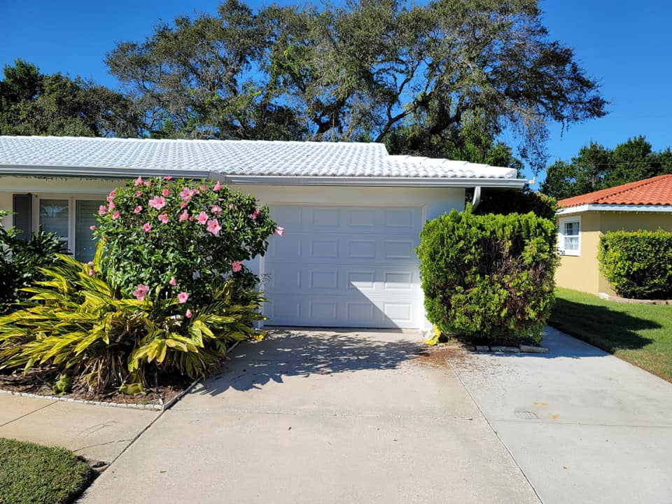 A white house with a white garage door and a driveway.