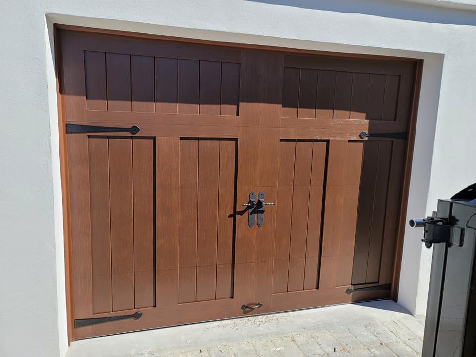 A wooden garage door with a black handle on a white wall