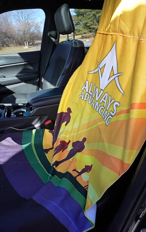 A towel in the back seat of a car that says always advancing