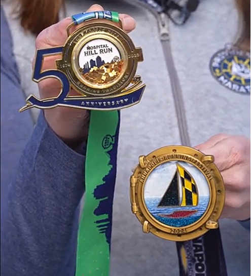 A person is holding two medals one of which has the number 5 on it