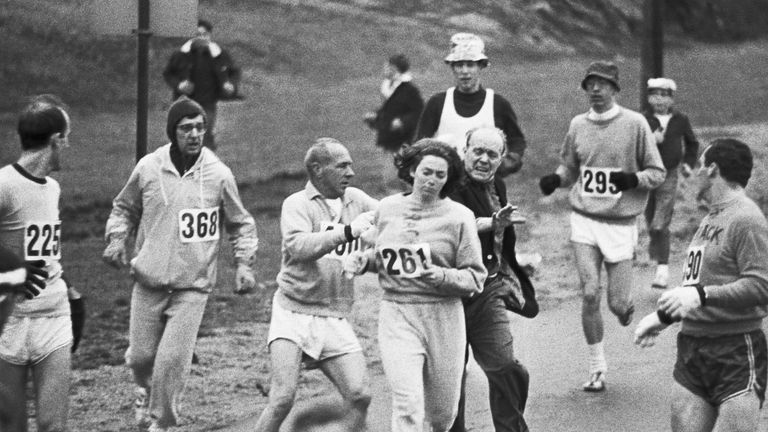 A black and white photo of a group of people running a race.