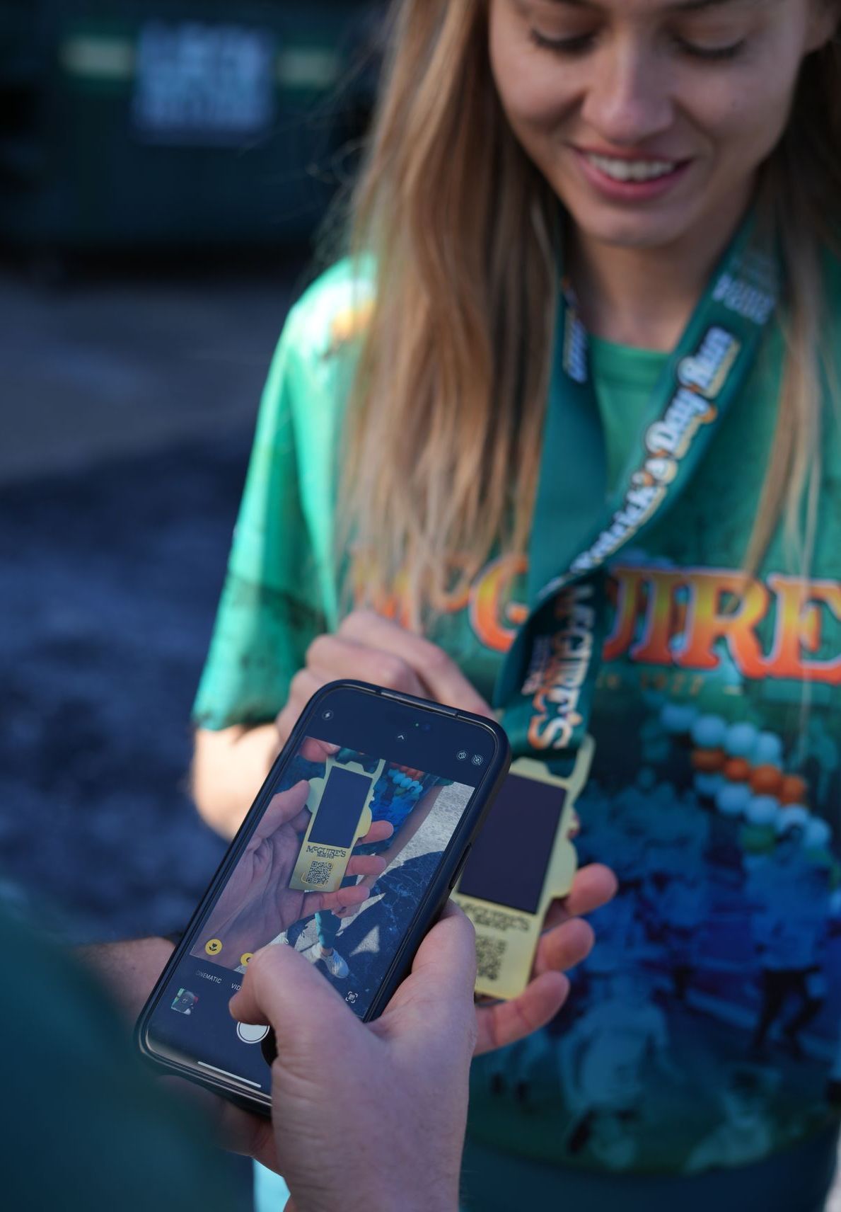A woman in a green shirt is holding a cell phone