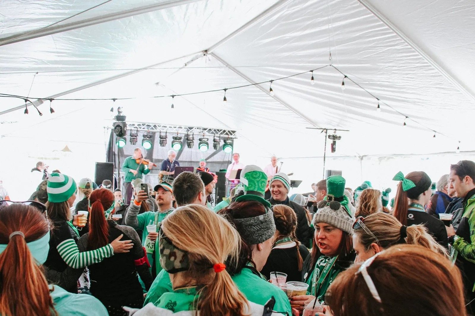 A large group of people are standing under a tent.