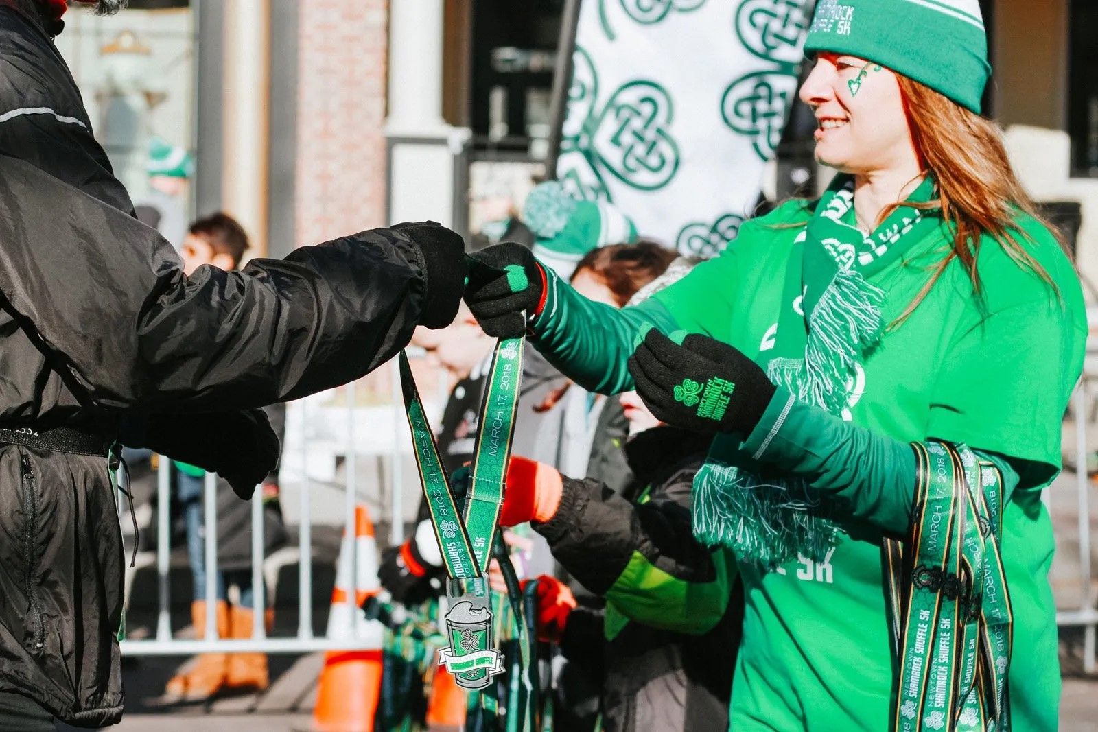 A woman in a green outfit is handing a medal to another woman.