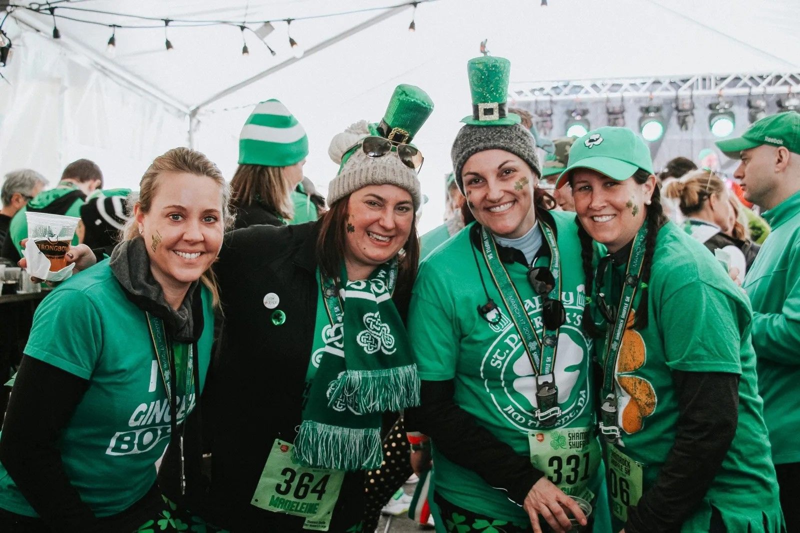 A group of women wearing green shirts and hats are posing for a picture.