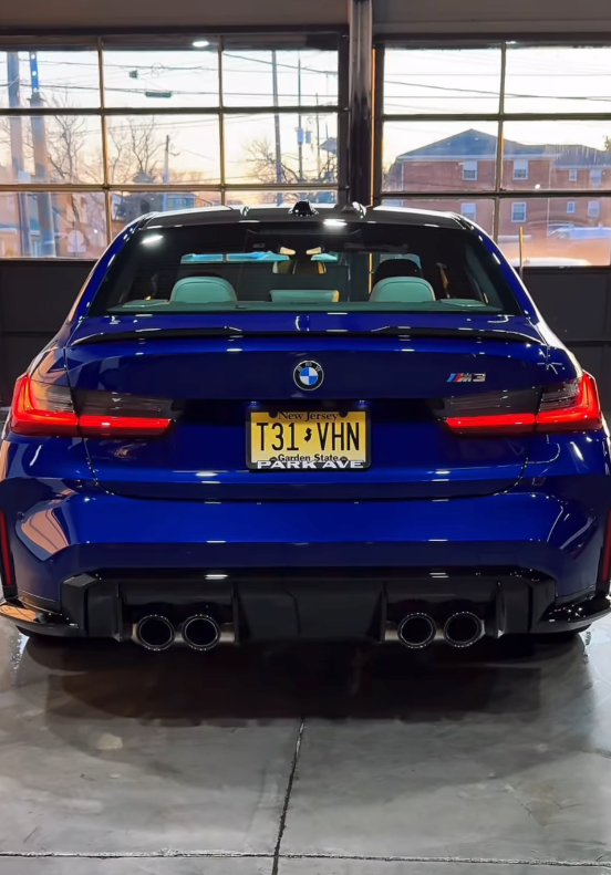 Blue BMW M3 parked indoors, rear view with yellow license plate and showroom windows in back | SA Performance