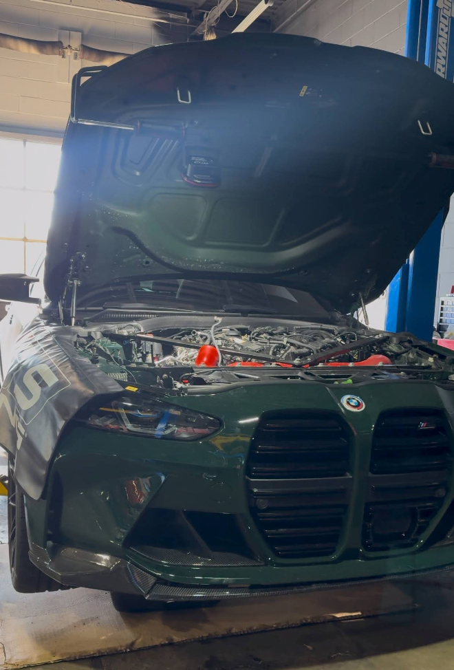 Dark green BMW in a garage with its hood open during maintenance | SA Performance