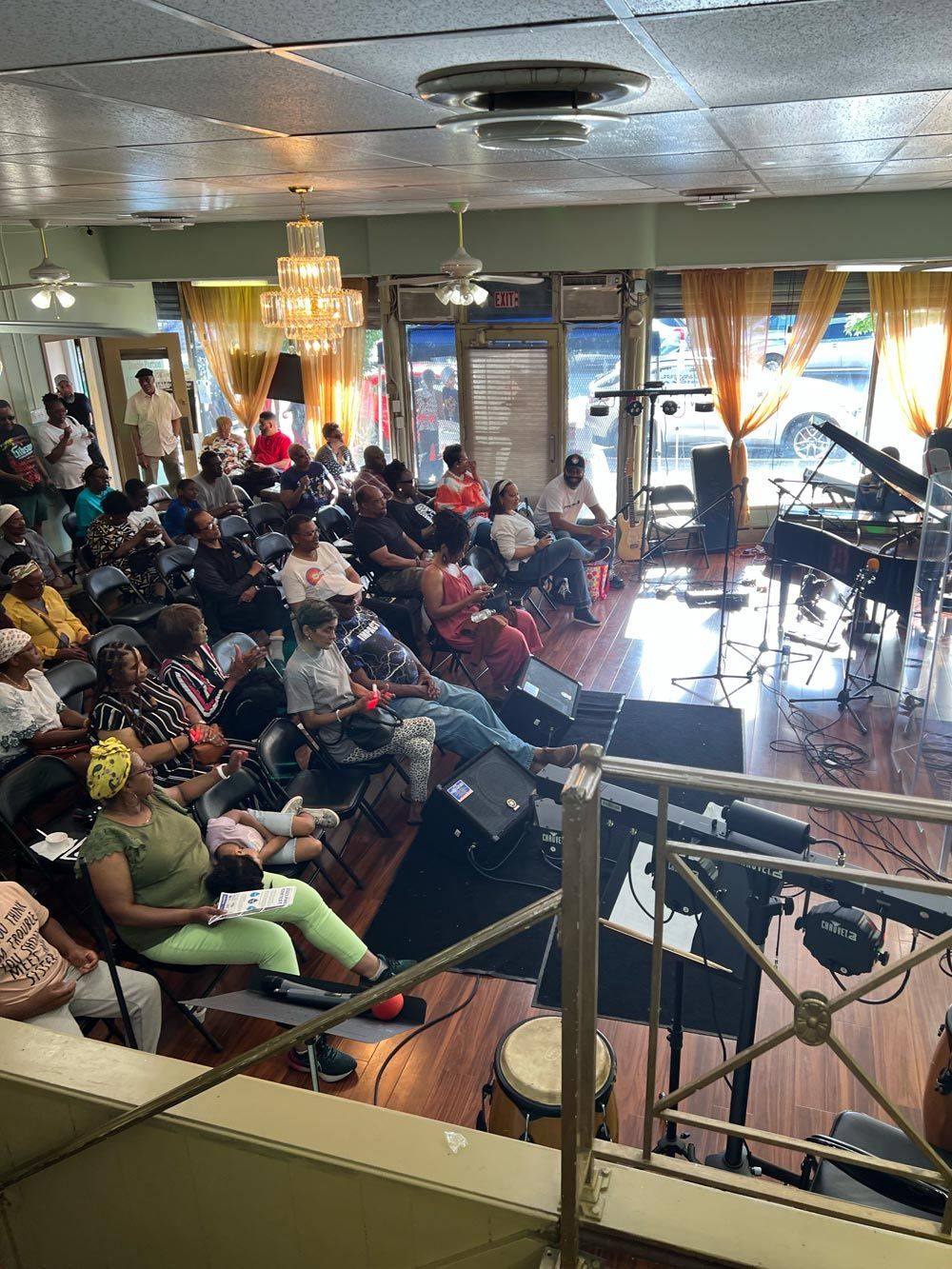 Audience seated in a café listening to a live performance on a small stage