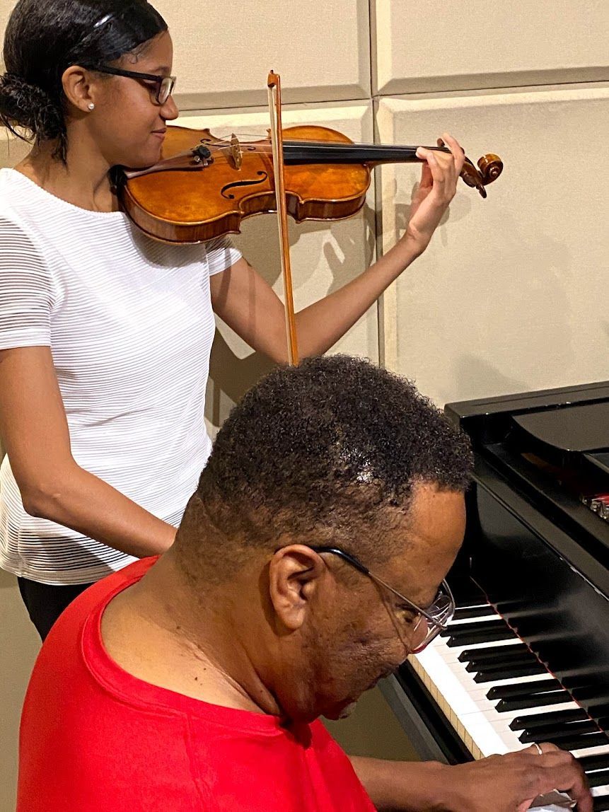 Two musicians playing violin and piano together indoors
