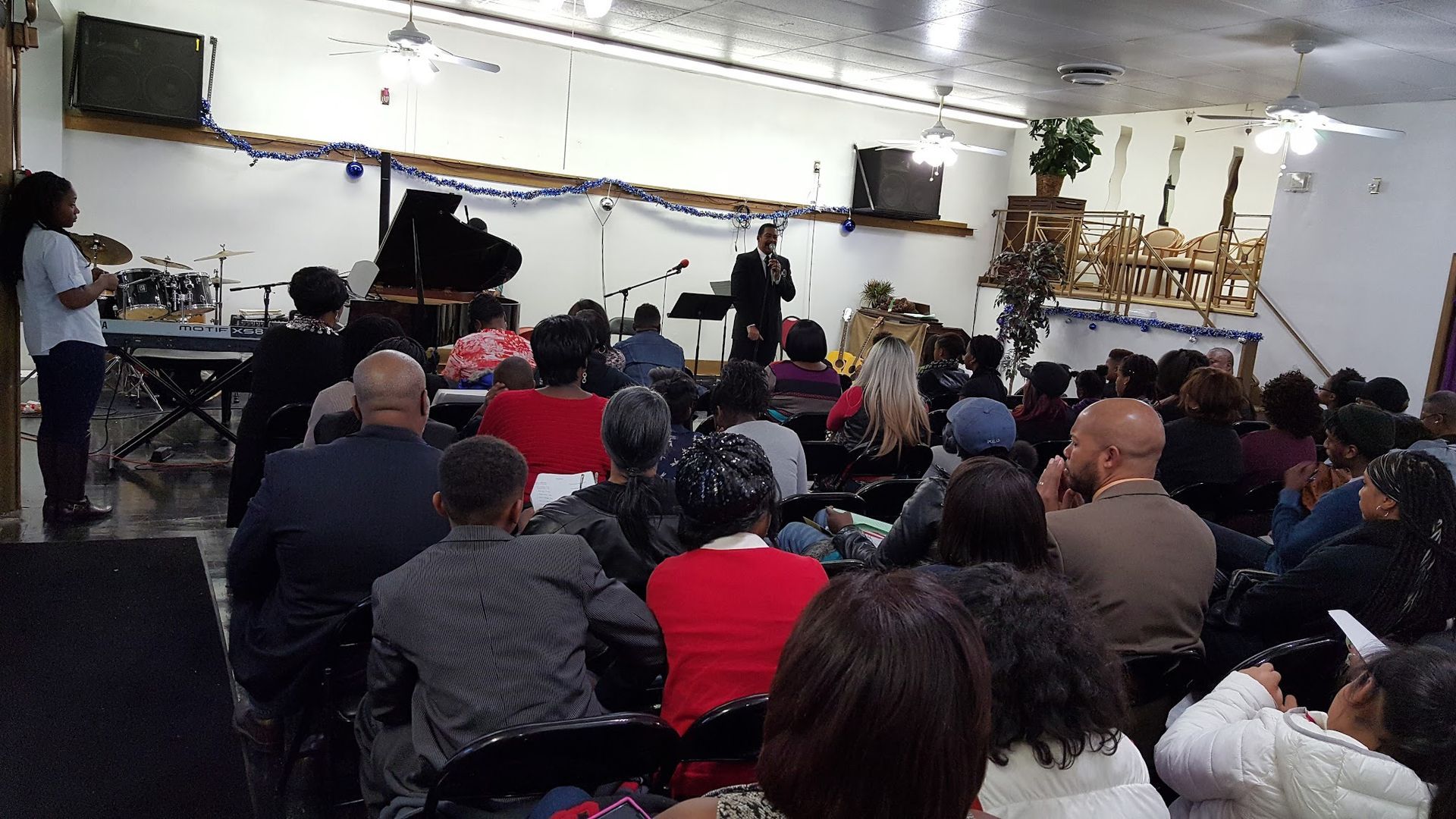 Audience seated in a hall watching a live performance on a small stage