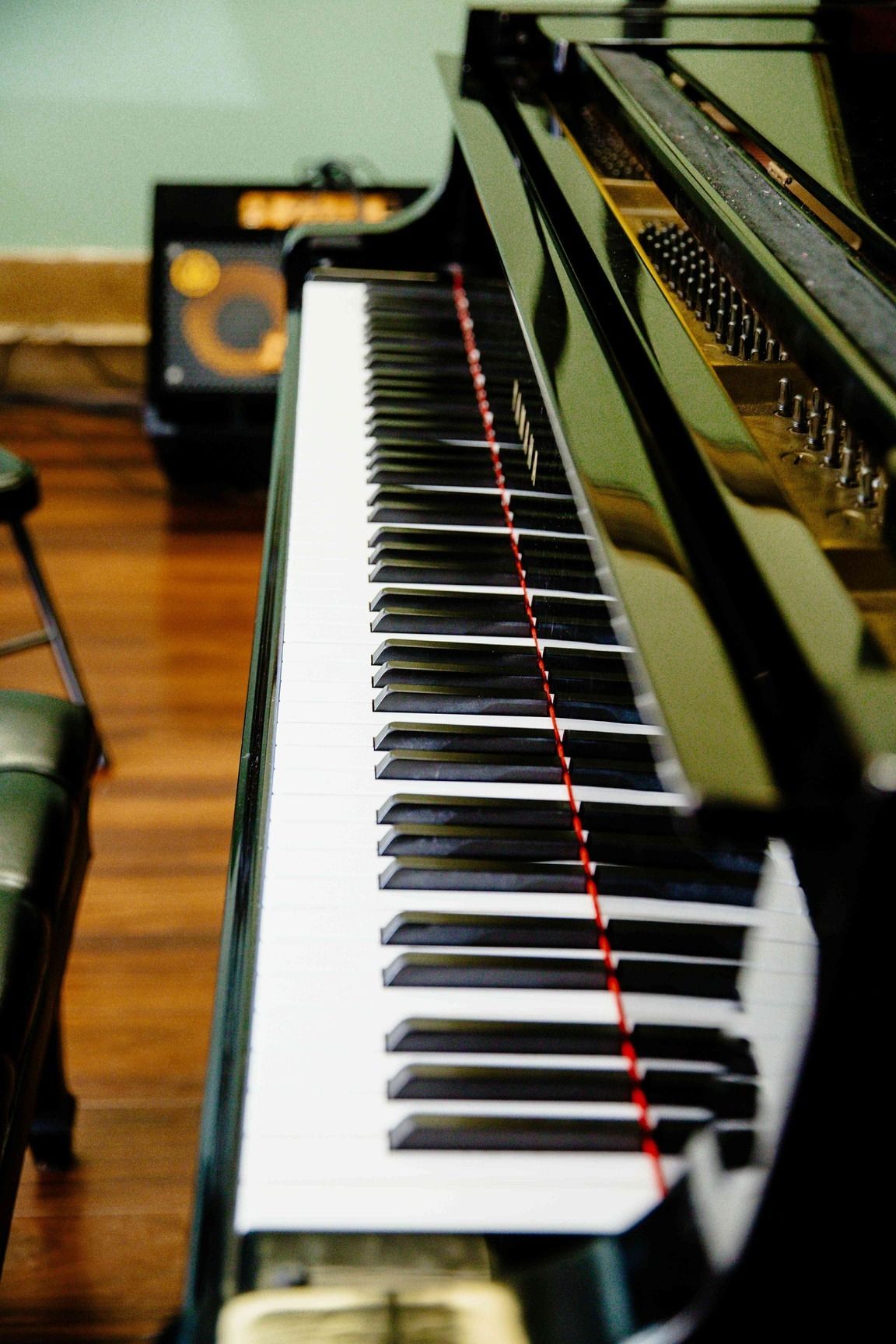 Black piano keyboard with glossy lid in a warm room, viewed from the end of the keys