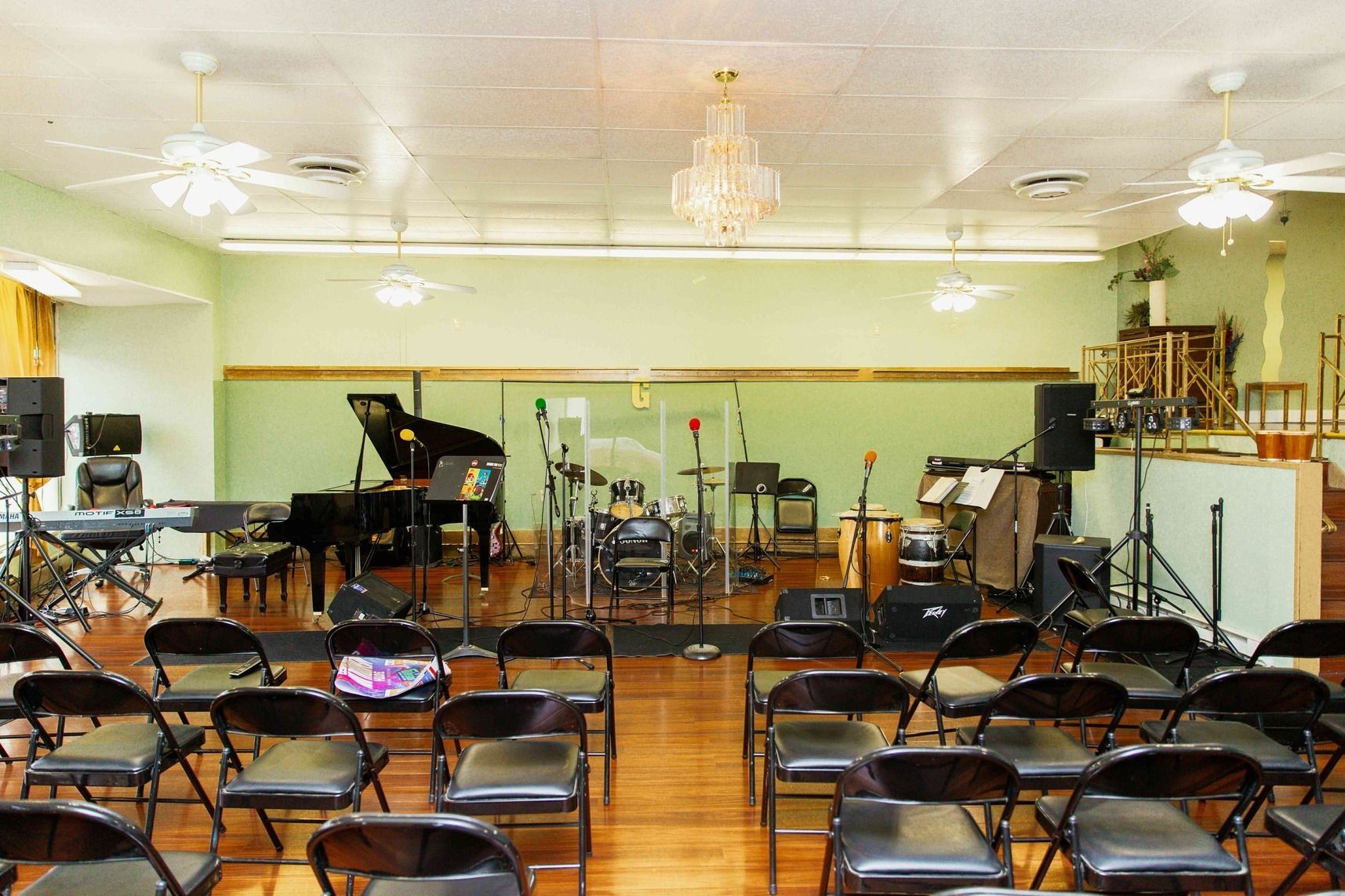 Empty church sanctuary with rows of folding chairs facing a stage with instruments and microphones