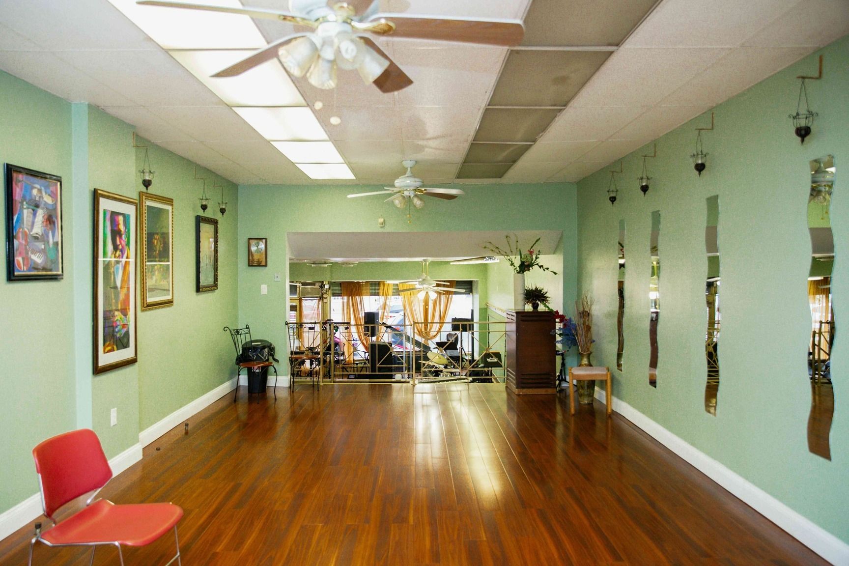 Empty dance studio with polished wooden floor, mint green walls, mirrors, and framed art.