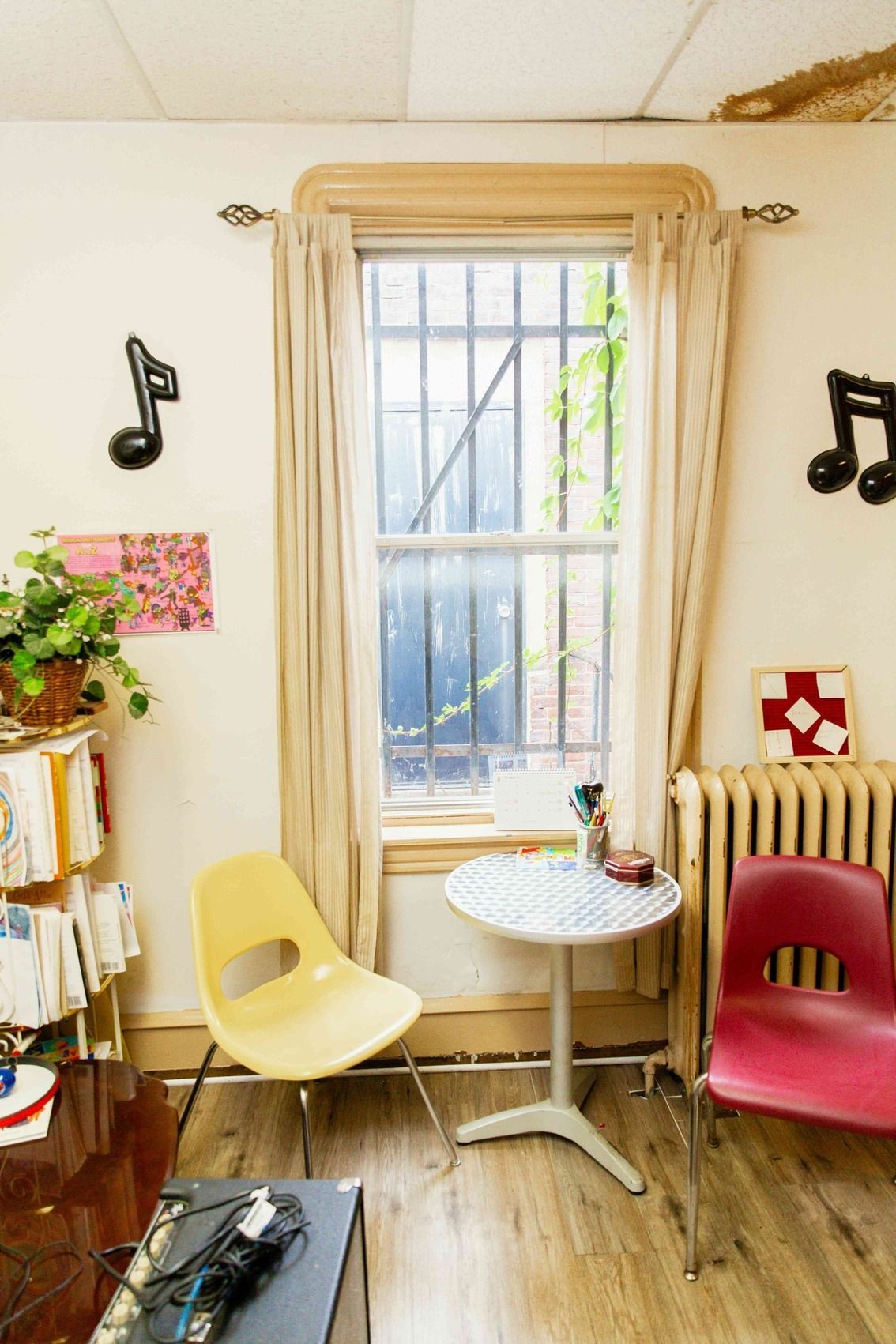 Cozy room with two colorful chairs, small table, window, and black music note wall decor