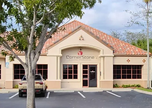 A car is parked in front of a building that says cornerstone