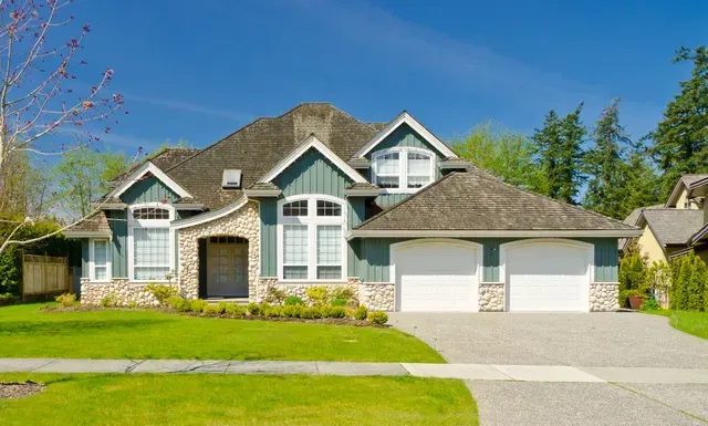 A large house with a slate roof and two garages