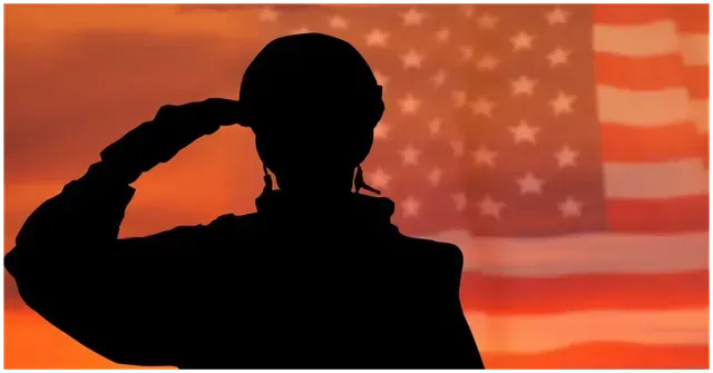 A silhouette of a soldier saluting in front of an american flag.