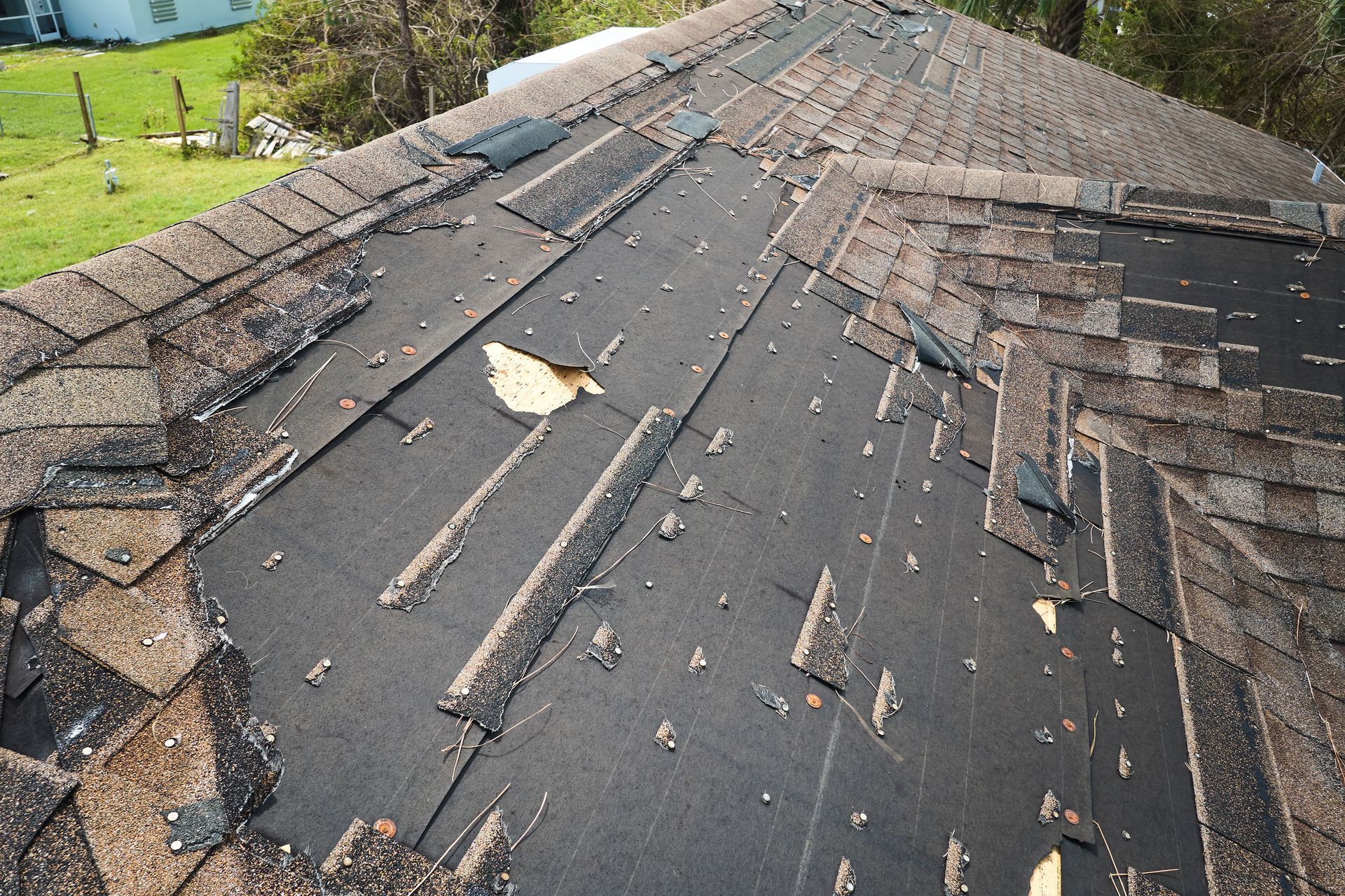 Damaged asphalt shingle roof with missing and torn areas. Damaged asphalt shingle roof with missing and torn areas.