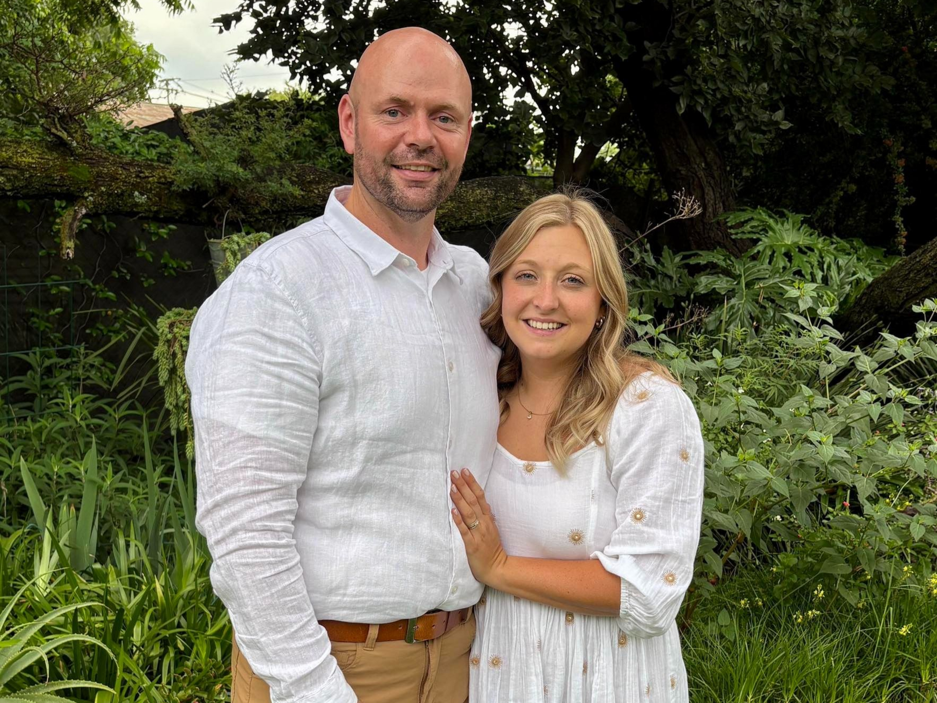 Smiling couple standing together in a lush green garden