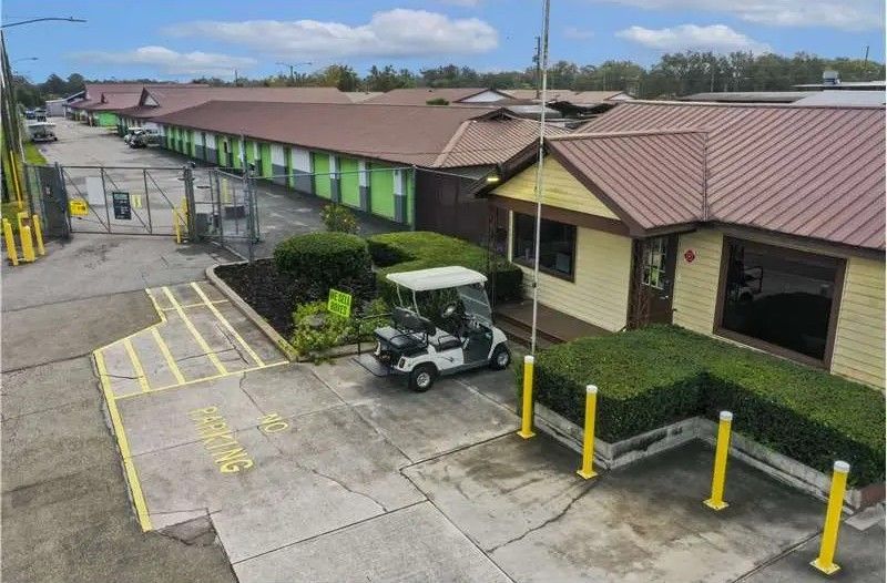 Parking lot beside motel rooms with a golf cart and yellow bollards near an accessible drop-off area