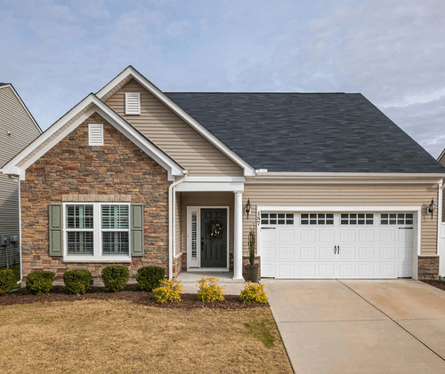 Single-story brick house with gray roof, front porch, and two-car garage