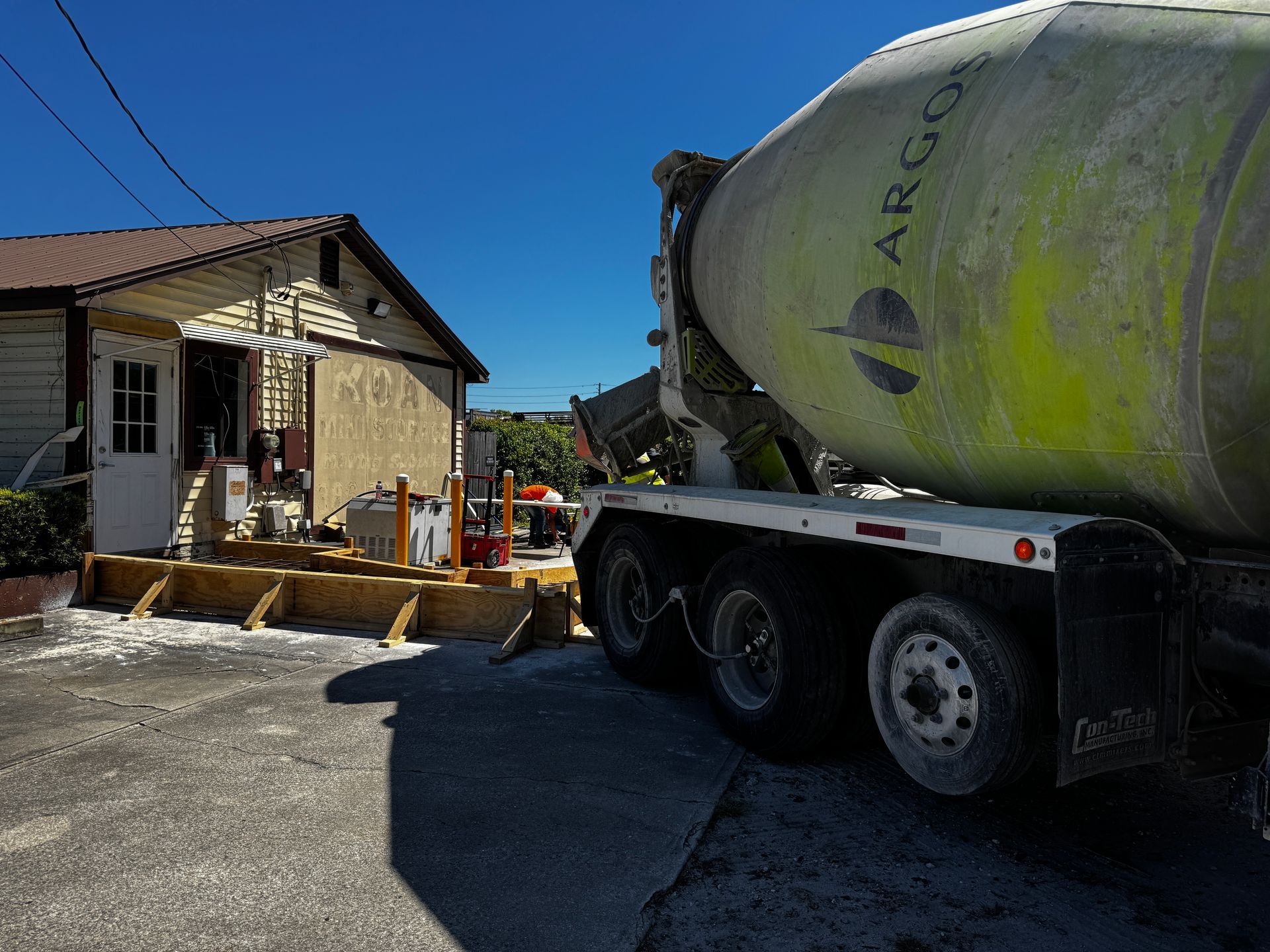 Concrete mixer truck beside a small house on a sunny residential street