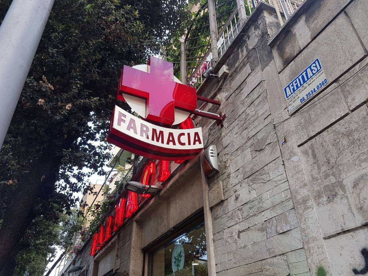 Insegna rossa della farmacia con croce e scritta 