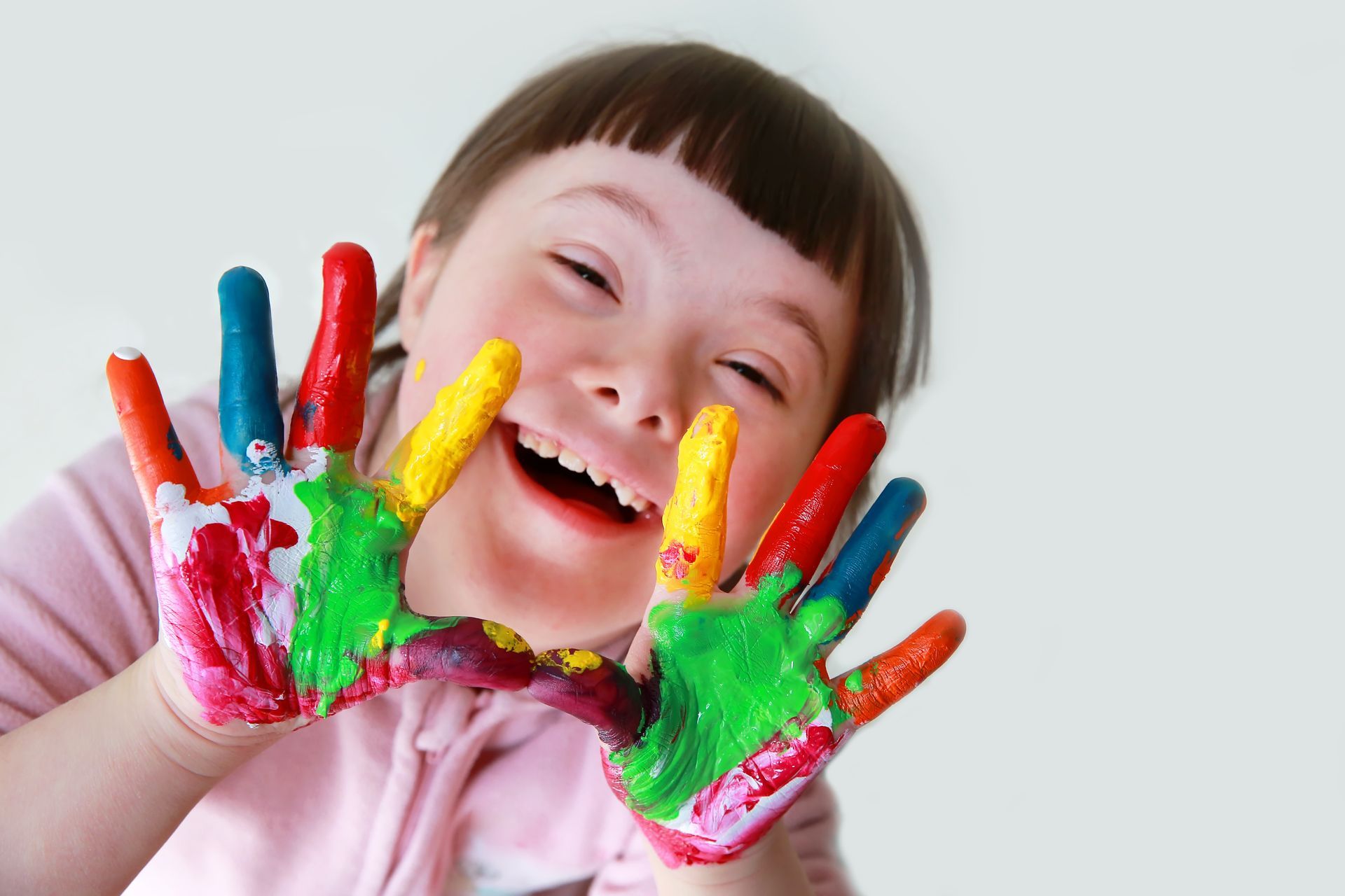 Close-up of a joyful child with colorful hands, highlighting inclusive special education play.