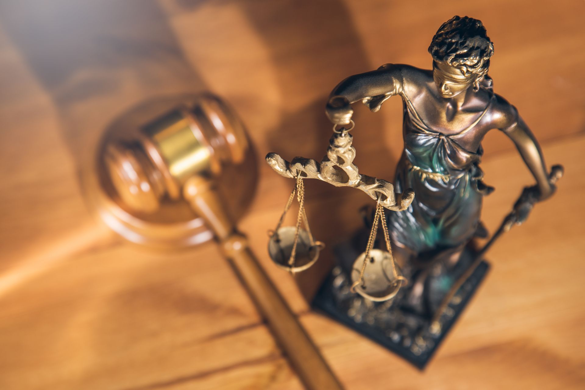 Lady Justice figurine beside a gavel on a wooden surface, symbolizing law and justice