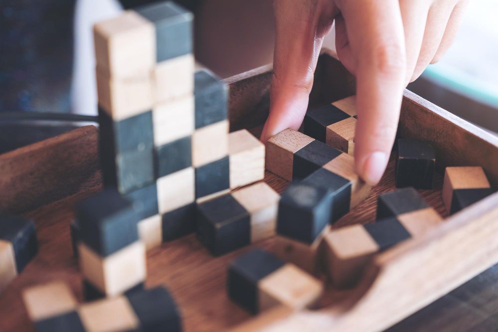 Placing wood blocks on a wood board by hand to solve a challenge.